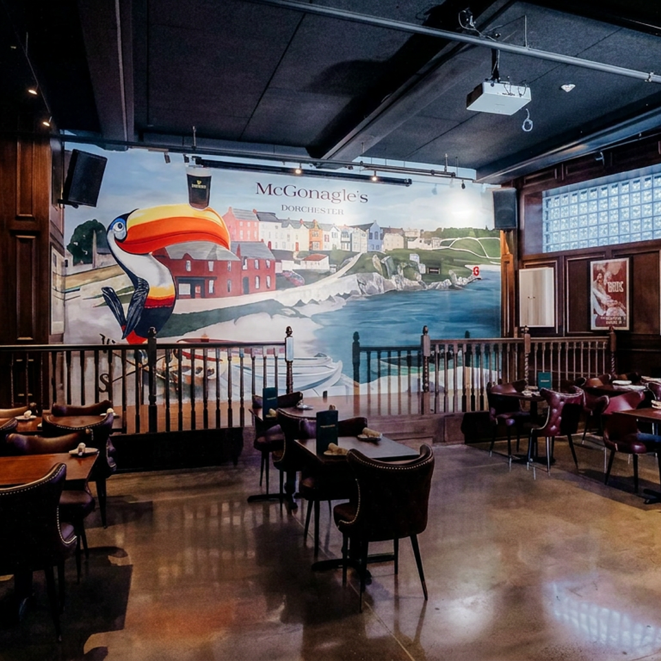 McGonagle’s Dorchester dining room with leather chairs, tables, framed posters, and a colorful coastal mural featuring a toucan.